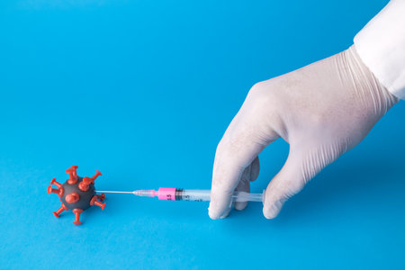 Hand injecting cure into coronavirus cell minimal creative concept.の写真素材