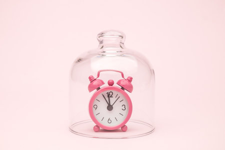 Alarm clock under glass cover quarantine minimal creative coronavirus concept.の写真素材