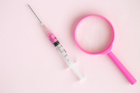 Flat lay of syringe and magnifying glass, minimal creative search coronavirus cure concept. Space...