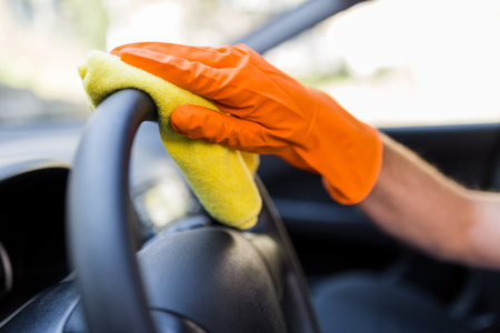 Hand in protective glove cleaning car steering wheel with microfiber cloth.の写真素材