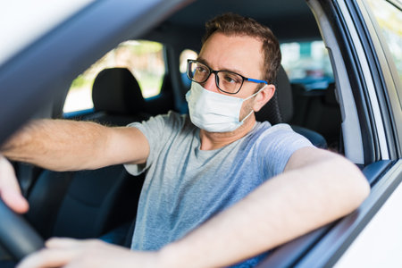 Male driver with protective face mask inside car.の写真素材
