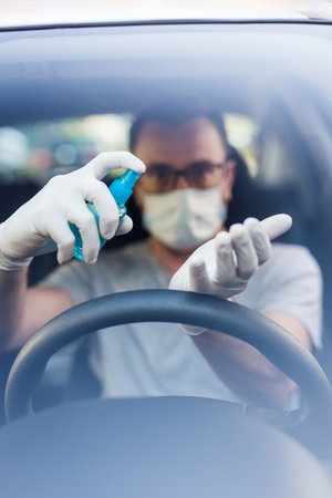 Close up of driver in protective mask with hands using alcohol hand sanitizer sprayer, covid-19 protection from bacteria and virus infection.の写真素材