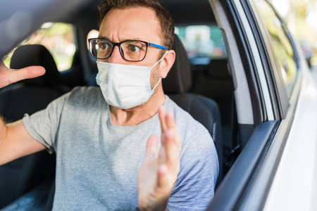 Male driver with protective face mask under stress inside car.の写真素材