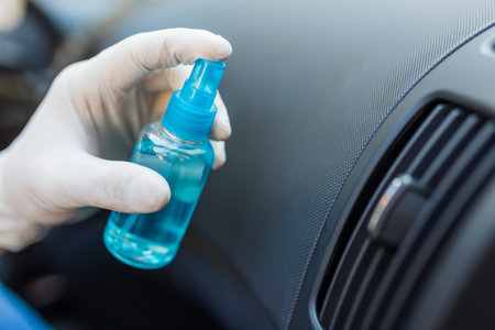 Close up of hand in rubber gloves holding disinfectant and spraying car air duct.の写真素材
