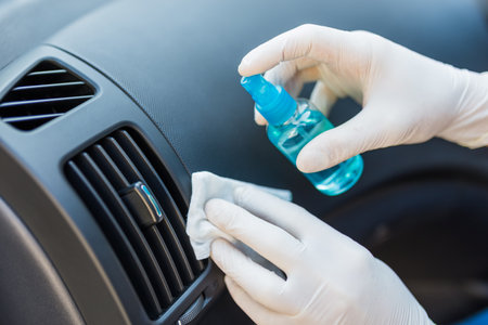 Man cleansing car dashboard vent grille air duct and spraying with disinfection liquid.の写真素材