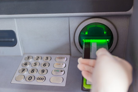 Close up of female hand wearing protective surgical glove and putting credit card into atm machine. Coronavirus concept.の写真素材
