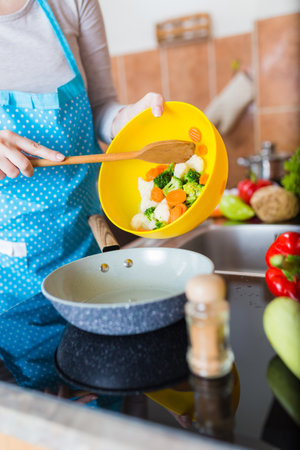 Housewife preparing healthy meal with various vegetables in kitchen.の写真素材