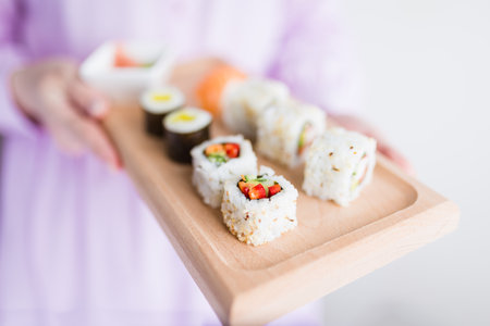 Close up of woman holding wooden platter sushi set. Japanese restaurant concept.の写真素材