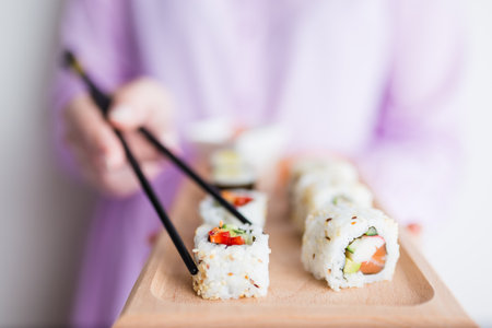 Close up of woman holding wooden platter sushi set and chopsticks.の写真素材