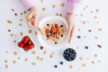 Flat lay of woman eating fresh muesli with fruits on table.の写真素材