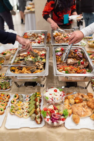 Hands picking up food from buffet catering table at the party.の写真素材