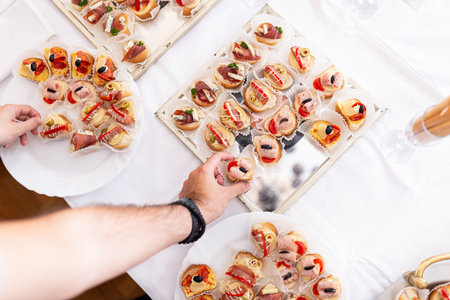 High angle view of man hand picking up canape from plate on the table.の写真素材