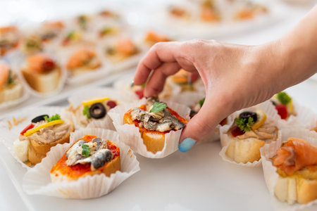 Close up of female hand holding canape. Buffet meal event concept.の写真素材
