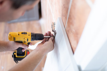 Man Assembling Shelf Using Electric Drill Tool At Home. Male Housework And House Furnishing. Handyman Fixing Wooden Cabinet During Renovationの写真素材