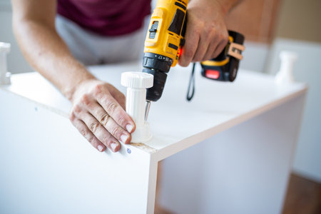 Man installing new furniture at his home and using cordless screwdriverの写真素材