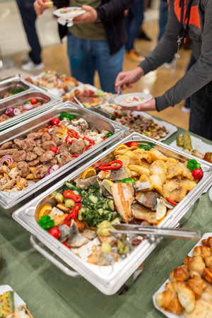 Warming dishes with food and people serving themselves. Buffet event concept.の写真素材
