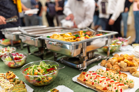 Warming tray with food and people in the background. Party lunch or dinner concept.の写真素材