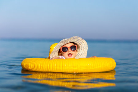 Sweet toddler baby girl in pool float ring enjoying summer day in the sea. Space for copy. Summer vacation and kids concepts.の写真素材