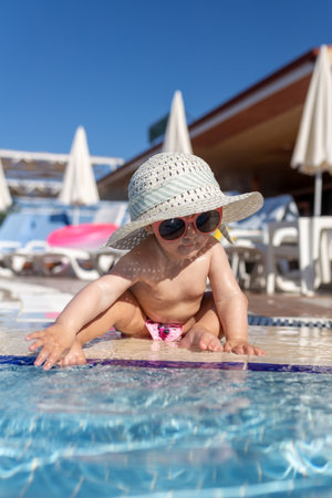 Portrait of little baby girl sitting next to swimming pool. Summer vacation and childhood concept.の写真素材