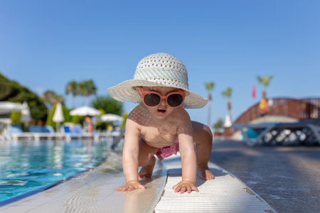 Portrait of little baby girl crawling at the poolside. Summer vacation and childhood concept.の写真素材