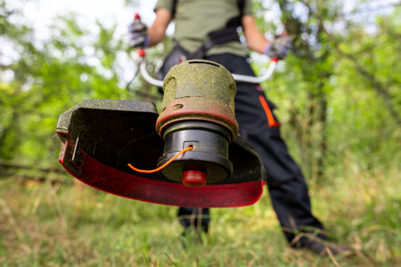 Close up of man using grass trimmer for cutting lawn in his garden.の写真素材