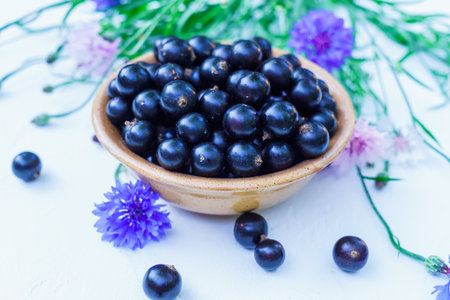 Fresh berries of black currant in a plate on a table. For a diet and saturation with vitaminsの写真素材