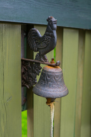 A small metal bell on an old wooden gate
