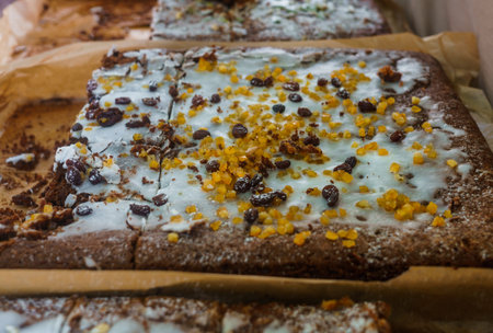 Delicious baked honey homemade cake, filled with glaze and sprinkled with candied fruits and raisins.の写真素材