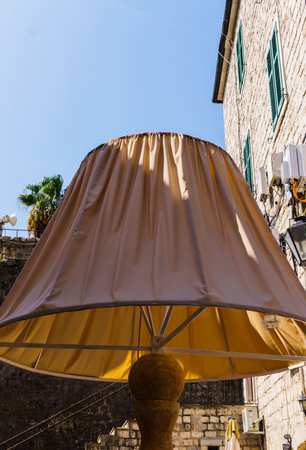 Decorative lampshade in the form of a bench for people.People walking on old town street in Kotor, Montenegro.September 25, 2018のeditorial素材
