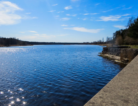 Dark blue water on the Lielupe River with glare from the bright sun in Latvia in early spring.の写真素材
