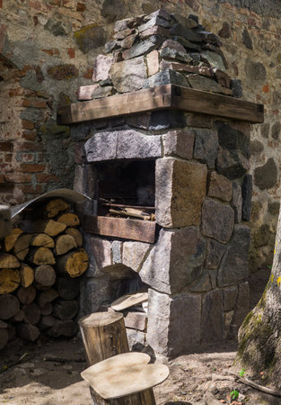 Stone fireplace for frying meat, laid out on the street against the wall, along with firewoodの写真素材