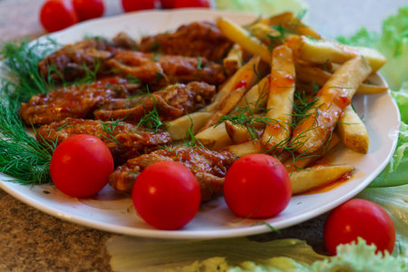 Chicken ribs in honey sauce with french fries and vegetableの写真素材