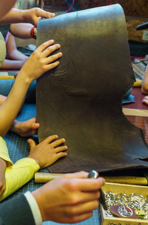 Children's hands are looking at a piece of leather in the workshopの写真素材
