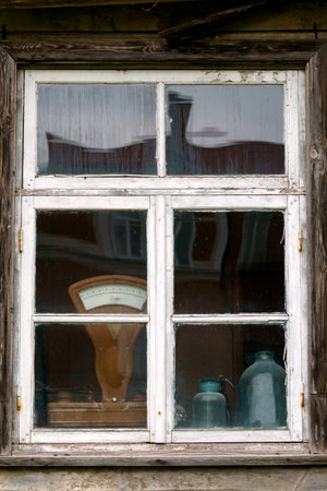 An old wooden window in a house with objects visible through the glass, standing on the windowsillの写真素材