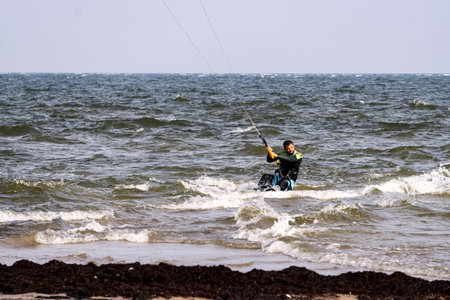 A young man is engaged in extreme kiteboarding in the Gulf of Riga on October 21, 2020 at Cape Kolka in Latvia.のeditorial素材