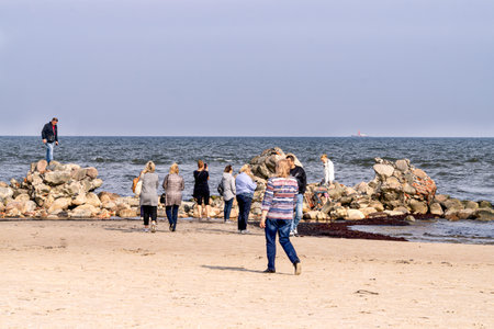Tourists take pictures of the lightest stone boulders of the breakwater on the coast of the Gulf of Riga at Cape Kolka.October 21, Latvia, 2020のeditorial素材