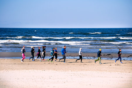 A group of people runs a marathon on the beach by the sea.の写真素材