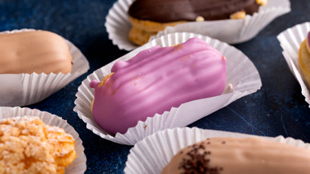 Beautiful delicious French eclairs with custard, covered with multi-colored icing.