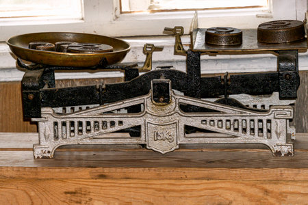Vintage metal scales for a store with weights on a wooden table.の写真素材