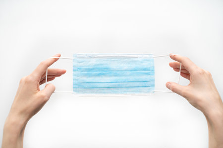 Putting on a disposable latex glove on a white background