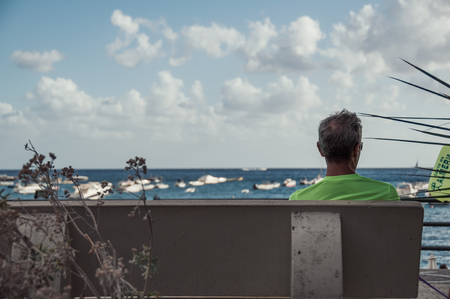 man sitting on the bench at the sea in Italyのeditorial素材