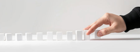 Hand arranging a row of white blocks on a white backgroundの素材