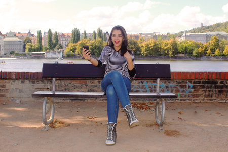 Teen girl sitting on a bench taking selfieの写真素材