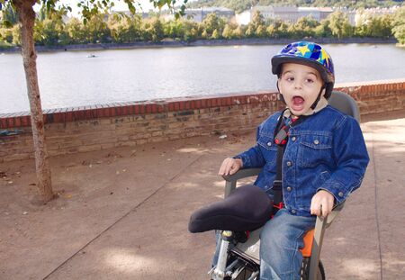 Little boy with a helmet sitting on a bike seatの写真素材