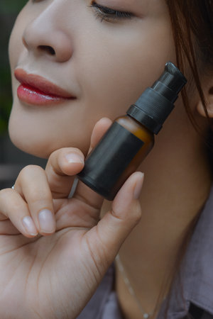 beautiful woman holding lotion packaging bottle display with close-up angleの写真素材