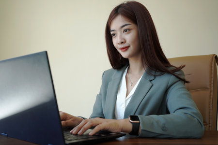 a female worker is working at her desk using a laptopの写真素材