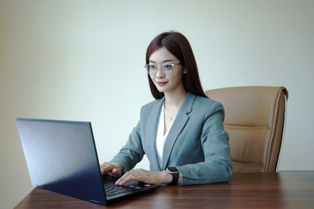 a female worker is working at a desk using a laptopの写真素材
