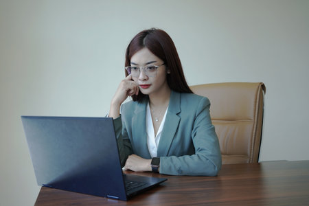 a female worker is working at her desk using a laptopの写真素材