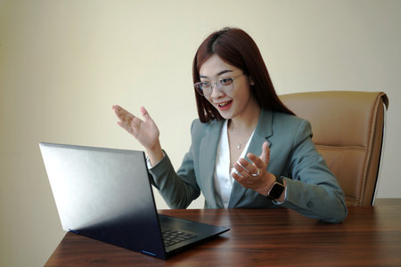 a female worker is working at her desk using a laptopの写真素材