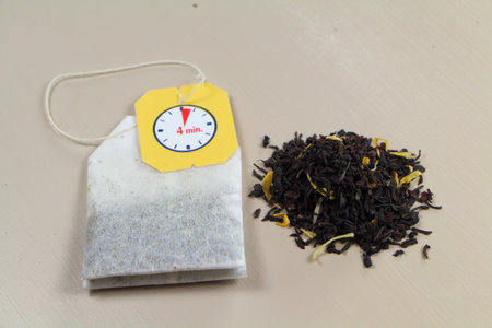 Tea bag near black tea leaves on a table